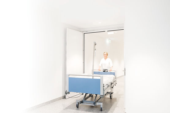 Un letto d'ospedale passa attraverso la porta tagliafuoco accessibile